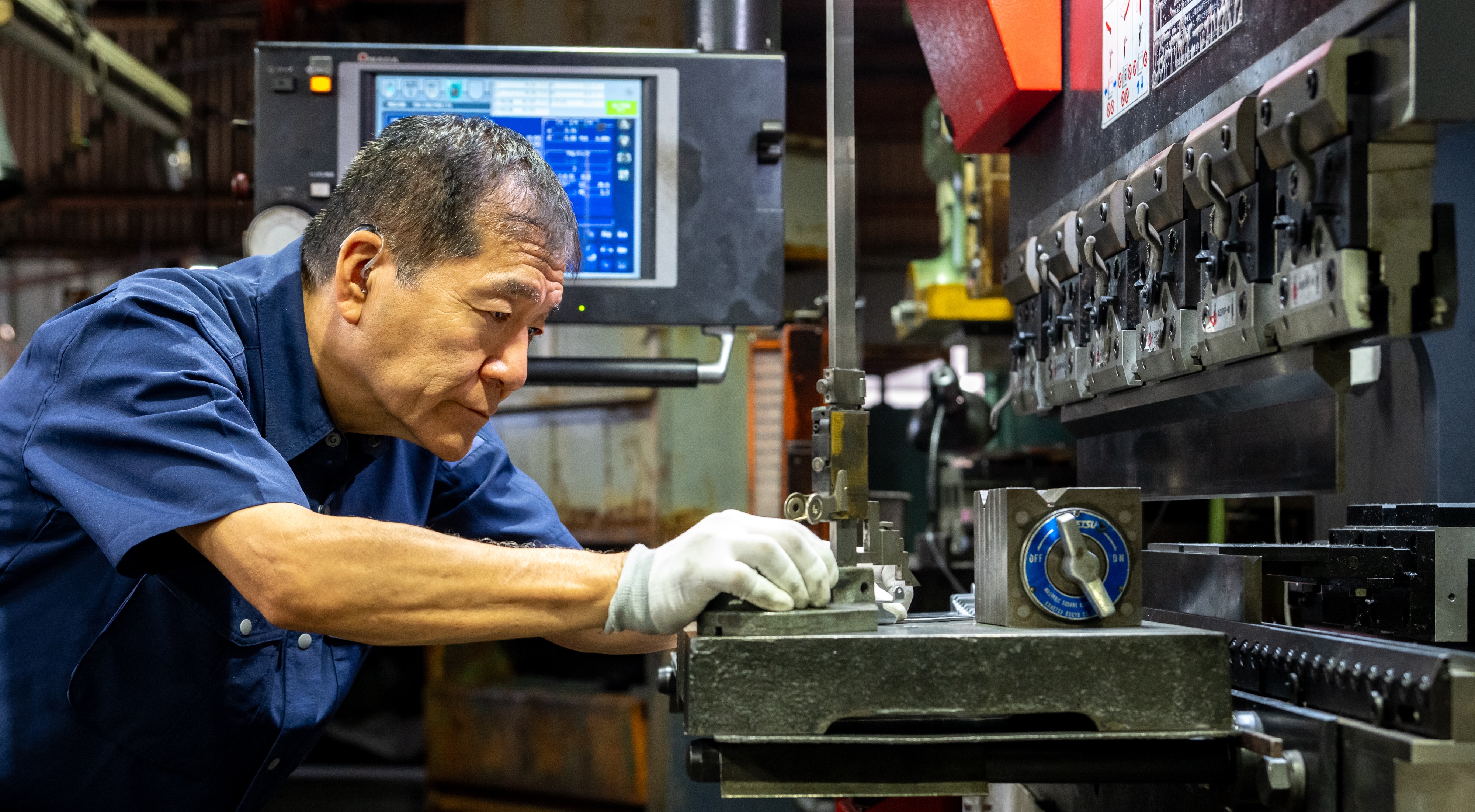バンドソーで金属を加工する土屋製作所の職人